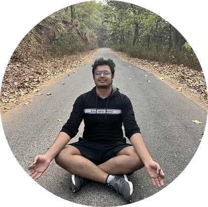 Daksh sitting cross-legged on a forest road, meditating